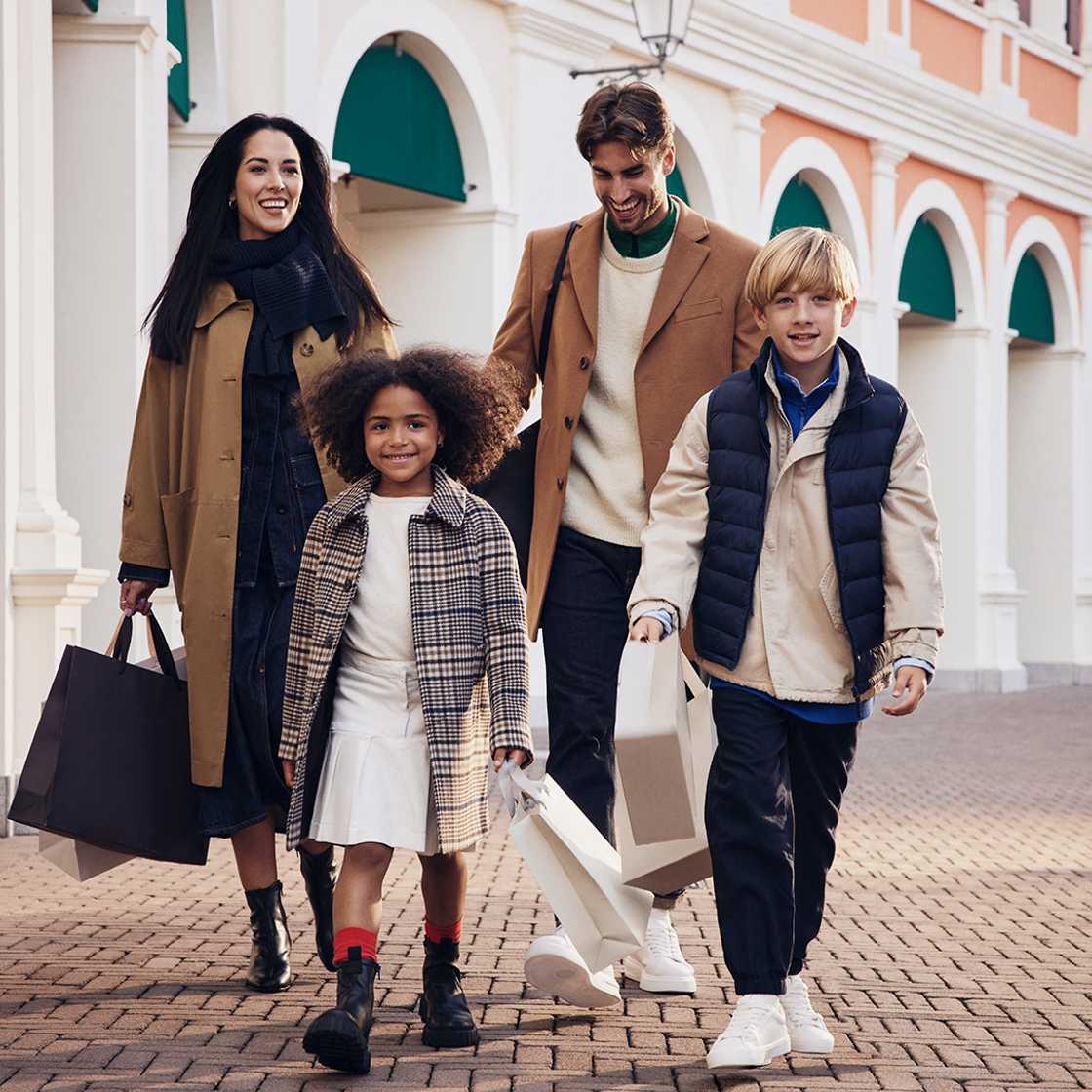 A happy family walking with shopping bags and their dog